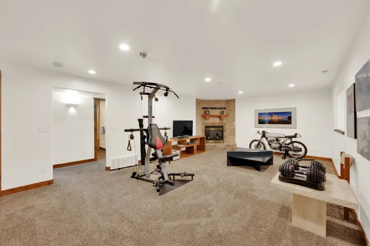 Workout area featuring light carpet, recessed lighting, and a tiled fireplace
