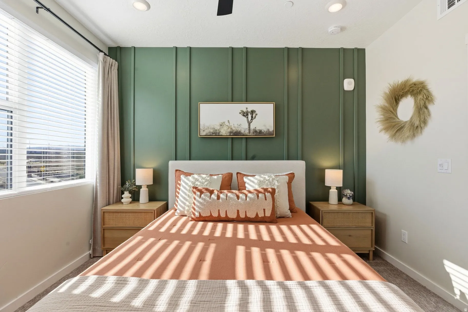 Bedroom with a decorative wall, carpet floors, and ceiling fan