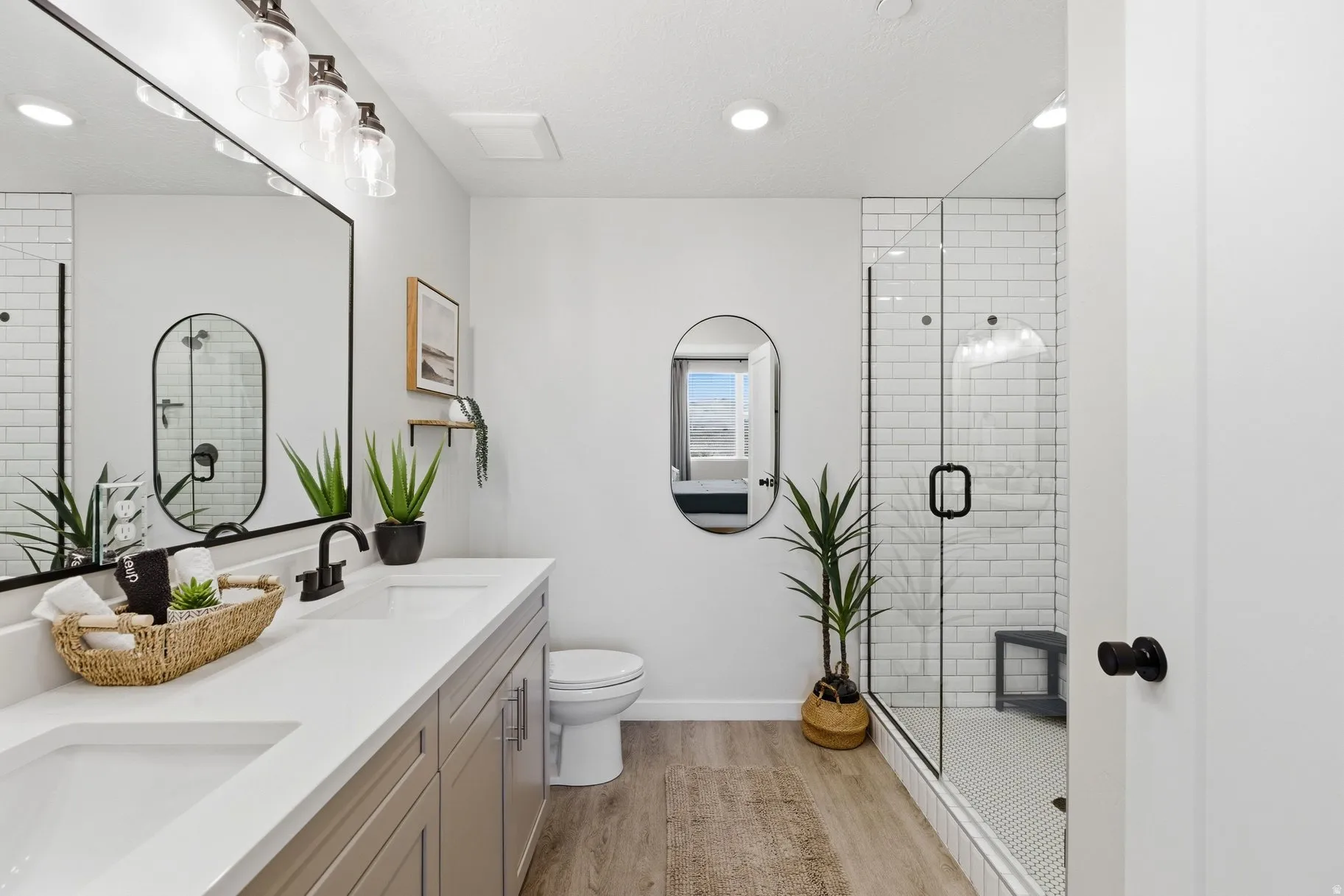 Full bathroom with double vanity, a stall shower, light wood-style floors, and recessed lighting