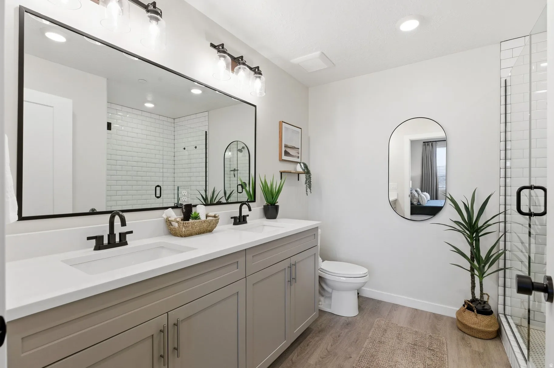 Bathroom with double vanity, a shower stall, light wood-style floors, and recessed lighting