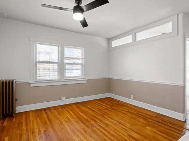 Spare room with radiator heating unit, light wood-type flooring, and a ceiling fan