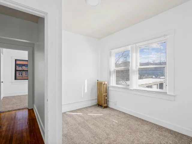 Carpeted empty room with radiator heating unit and baseboards