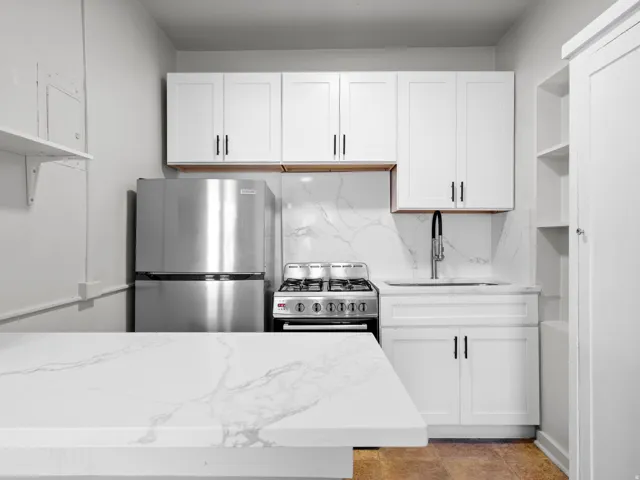 Kitchen featuring open shelves, light stone countertops, stainless steel appliances, and white cabinetry