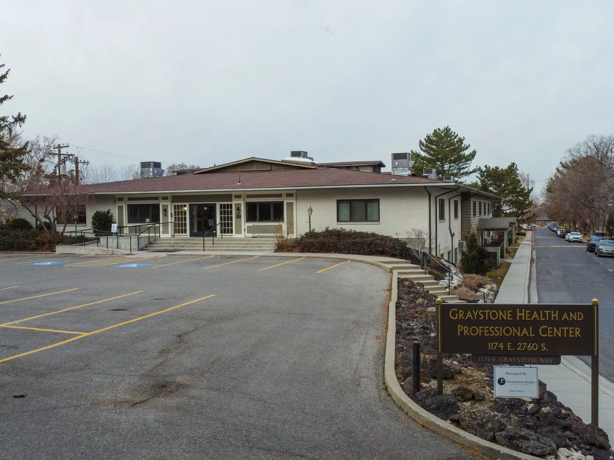 View of building exterior featuring uncovered parking and entry steps