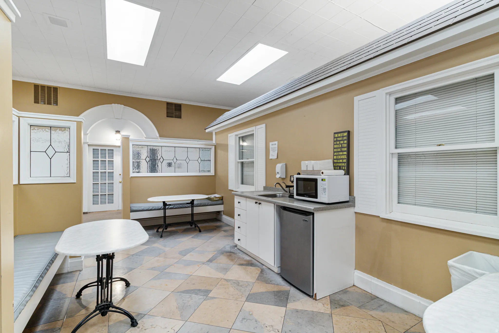 Kitchen with white cabinetry, white microwave, stainless steel fridge, crown molding, and light countertops