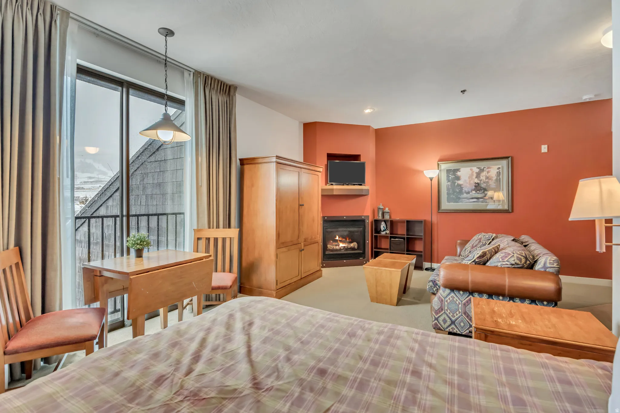 Bedroom with a glass covered fireplace and access to outside
