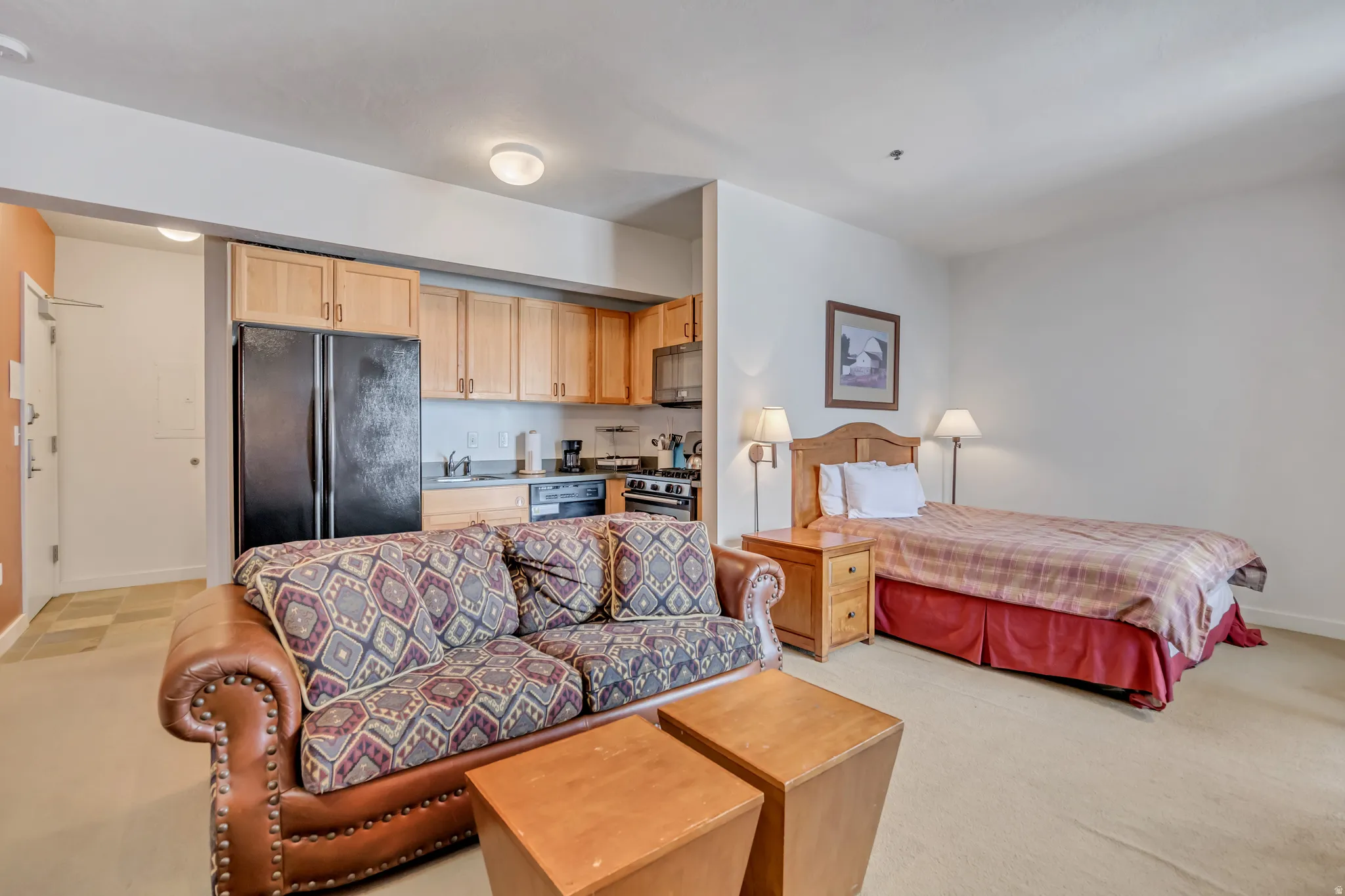 Bedroom featuring freestanding refrigerator and light carpet
