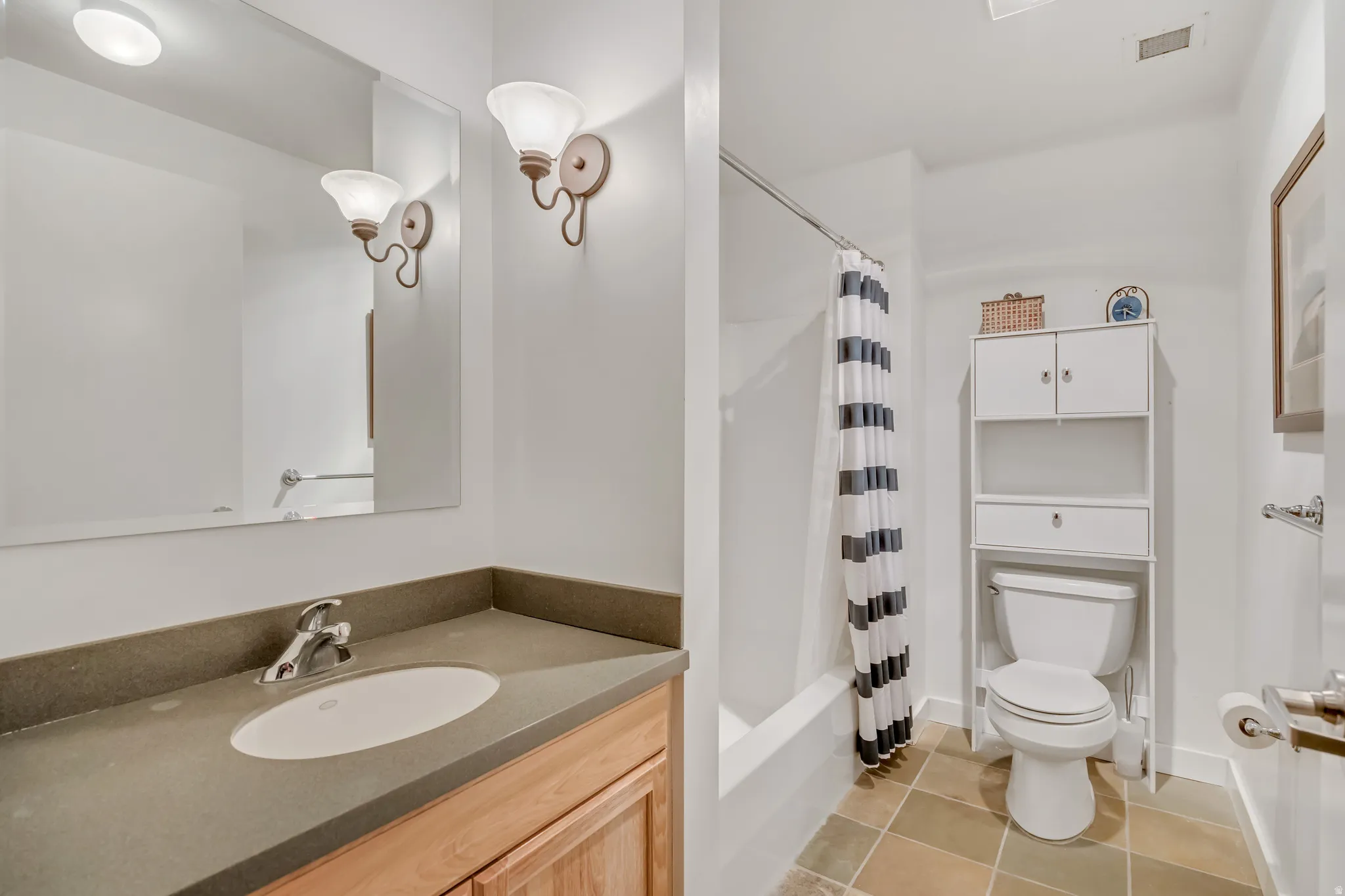 Bathroom with vanity, shower / bathtub combination with curtain, and light tile patterned floors