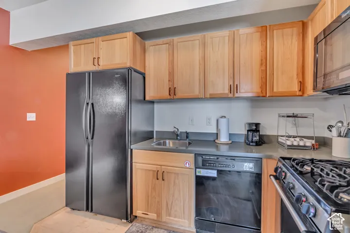 Kitchen featuring black appliances and light wood finish cabinetry