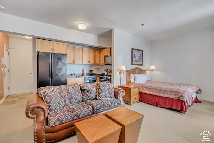 Bedroom featuring freestanding refrigerator and light carpet