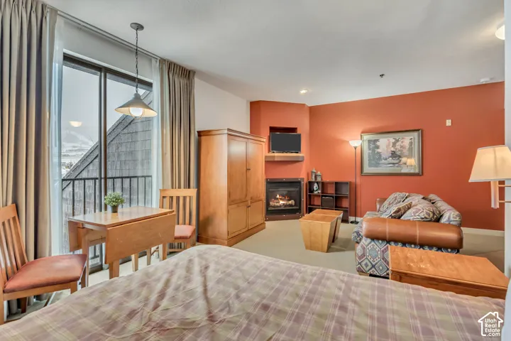 Bedroom with a glass covered fireplace and access to outside