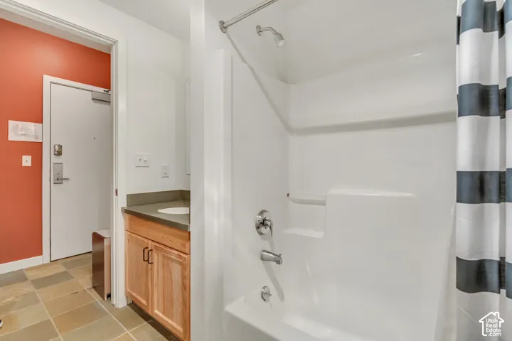 Bathroom featuring shower / bath combo with shower curtain, vanity, and light tile patterned floors