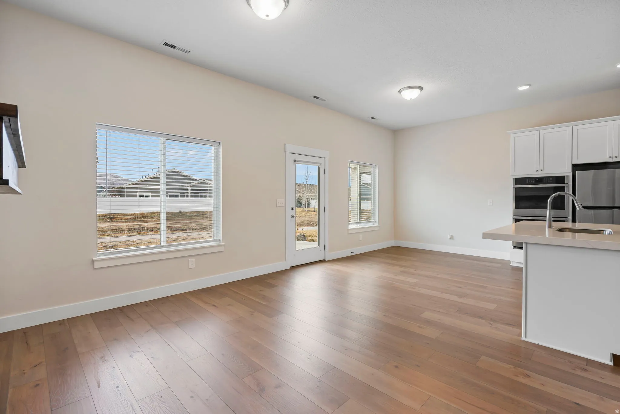 Kitchen with white cabinets, light wood-type flooring, stainless steel appliances, open floor plan, and recessed lighting