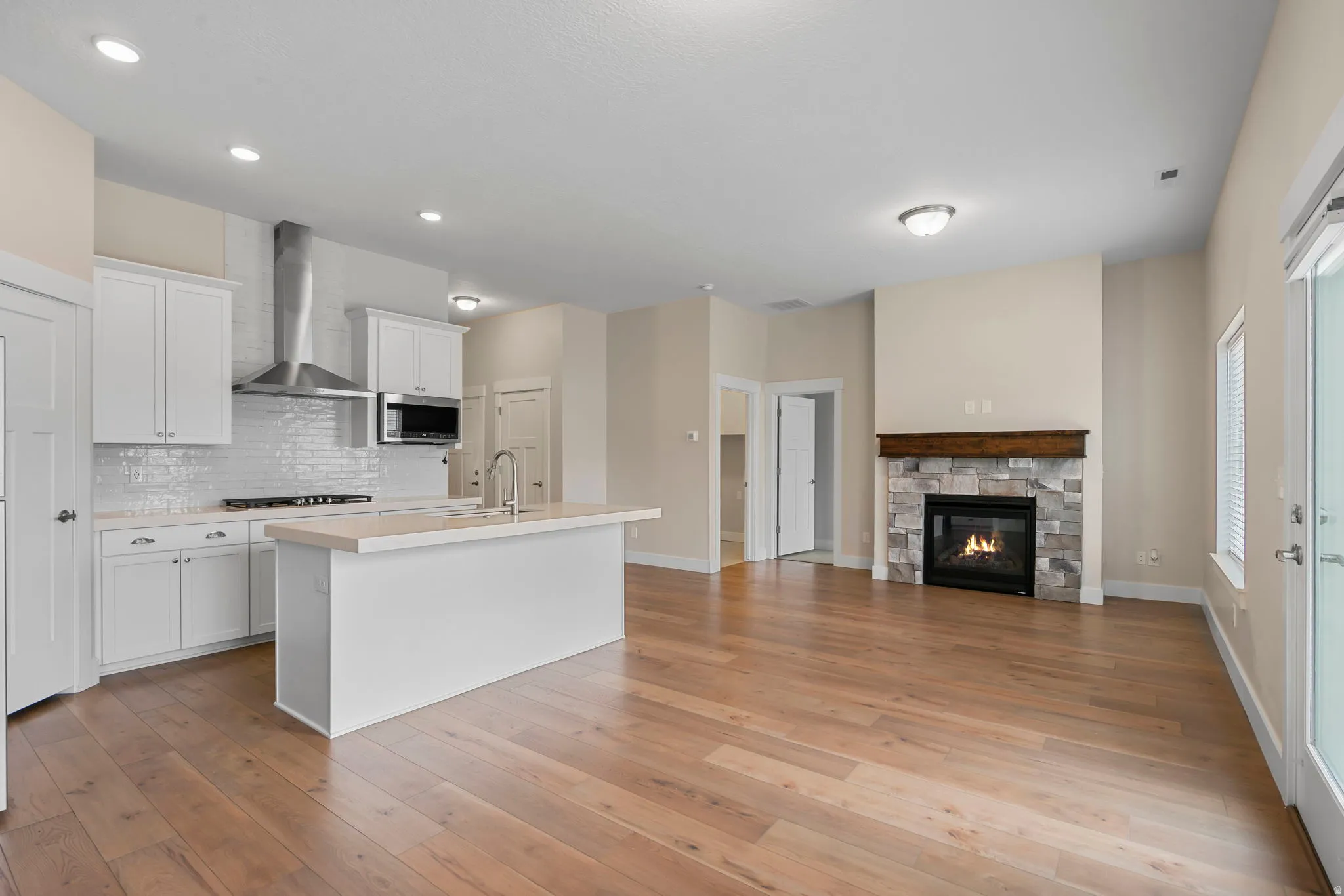 Kitchen with a stone fireplace, light countertops, a center island with sink, white cabinets, and open floor plan