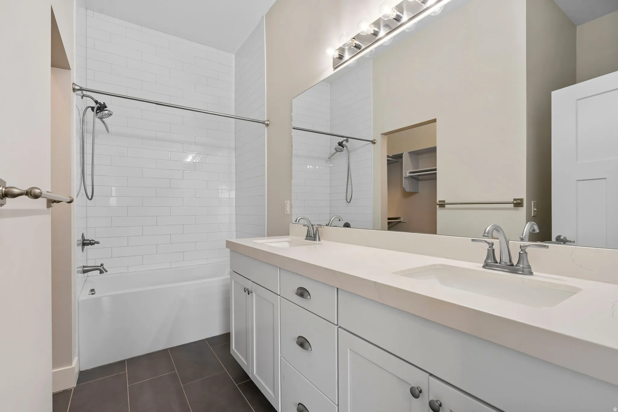 Full bathroom featuring double vanity,  shower combination, and dark tile patterned floors