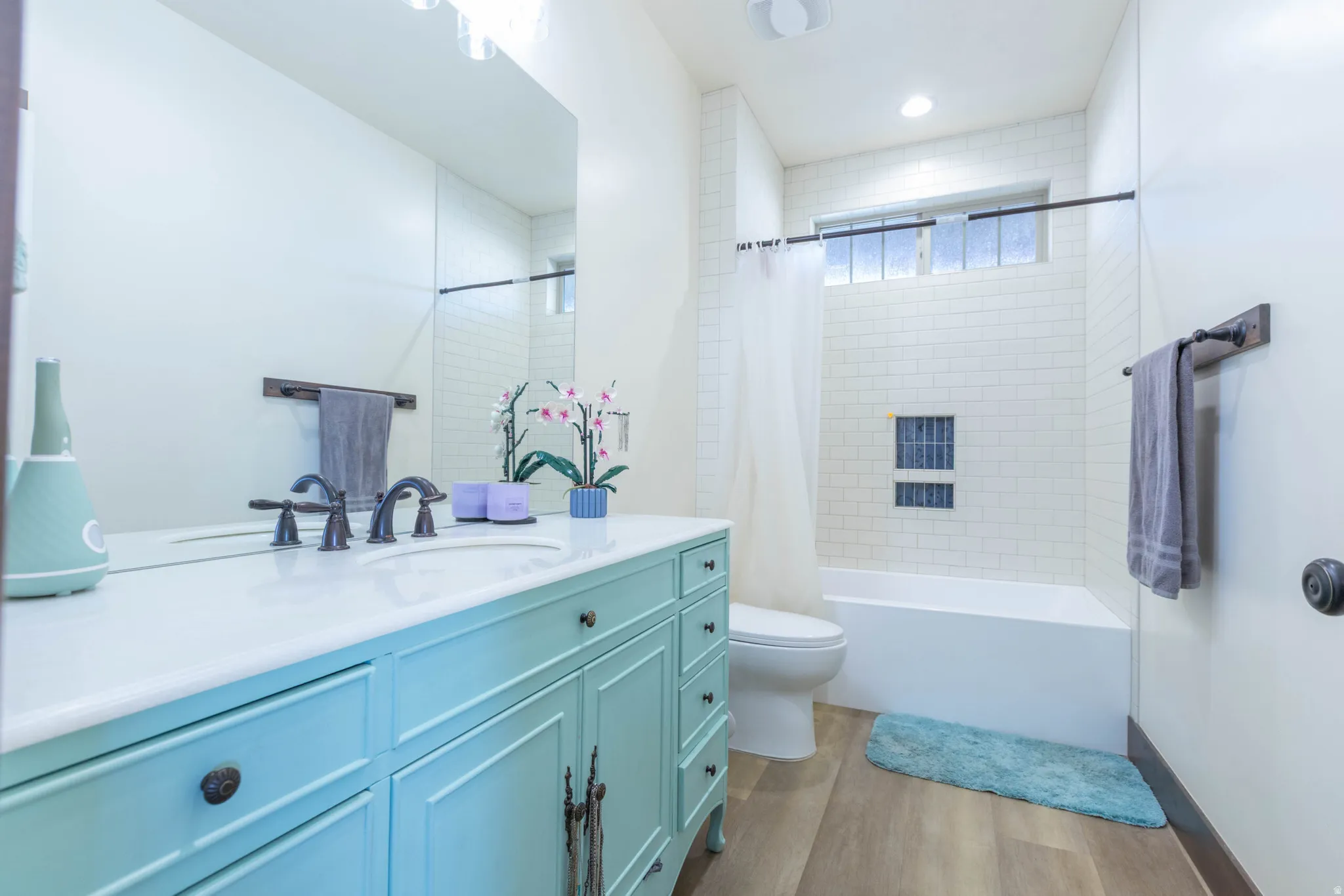 Full bathroom featuring vanity, shower / bath combination with curtain, and light wood-style flooring