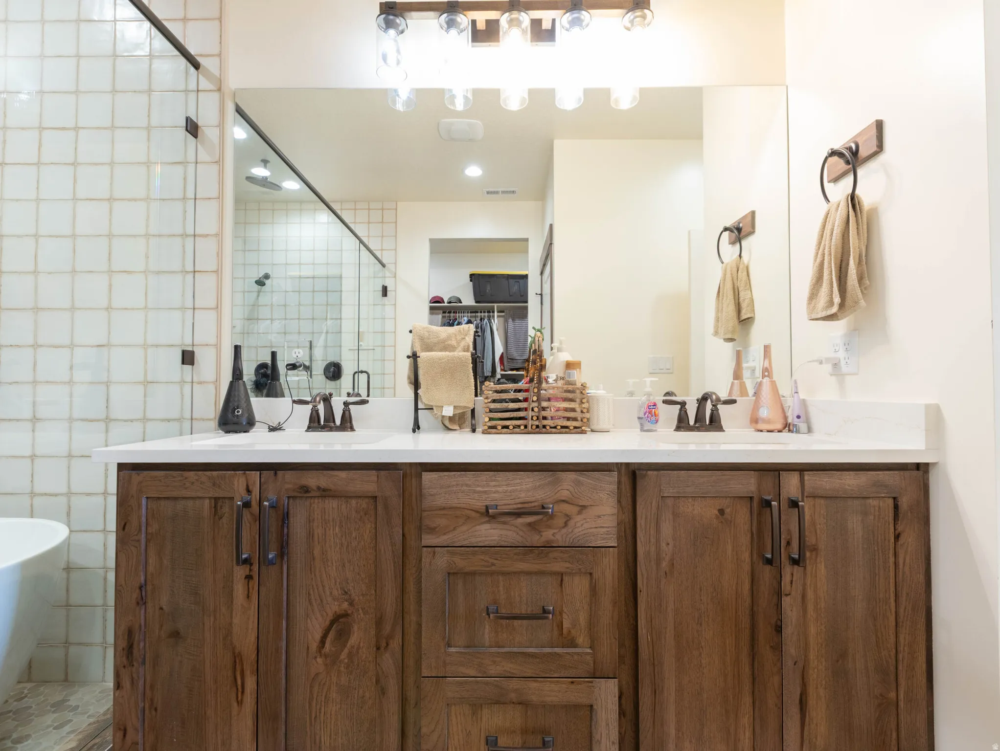 Full bathroom featuring double vanity, a spacious closet, a stall shower, and a freestanding tub