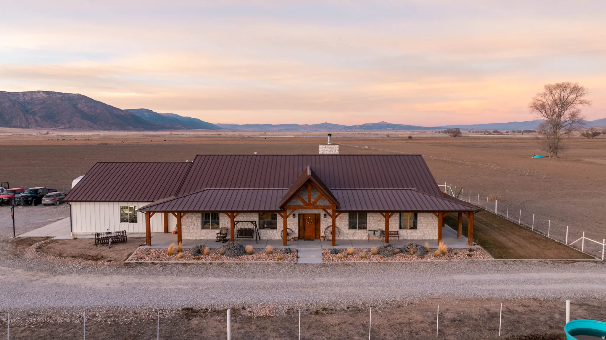 View of front facade with a chimney, covered porch, stone siding, and a standing seam roof