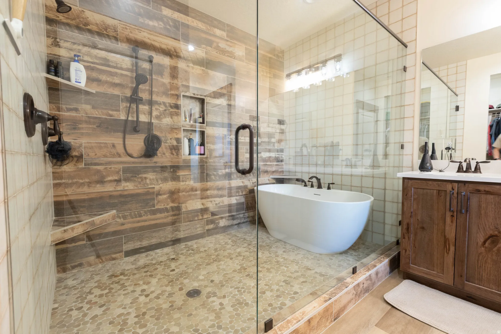 Bathroom with a shower stall, vanity, a freestanding bath, tile walls, and a walk in closet