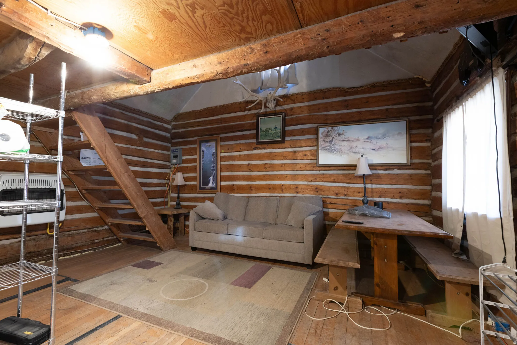 Living room featuring lofted ceiling with beams, hardwood / wood-style flooring, heating unit, and wood walls