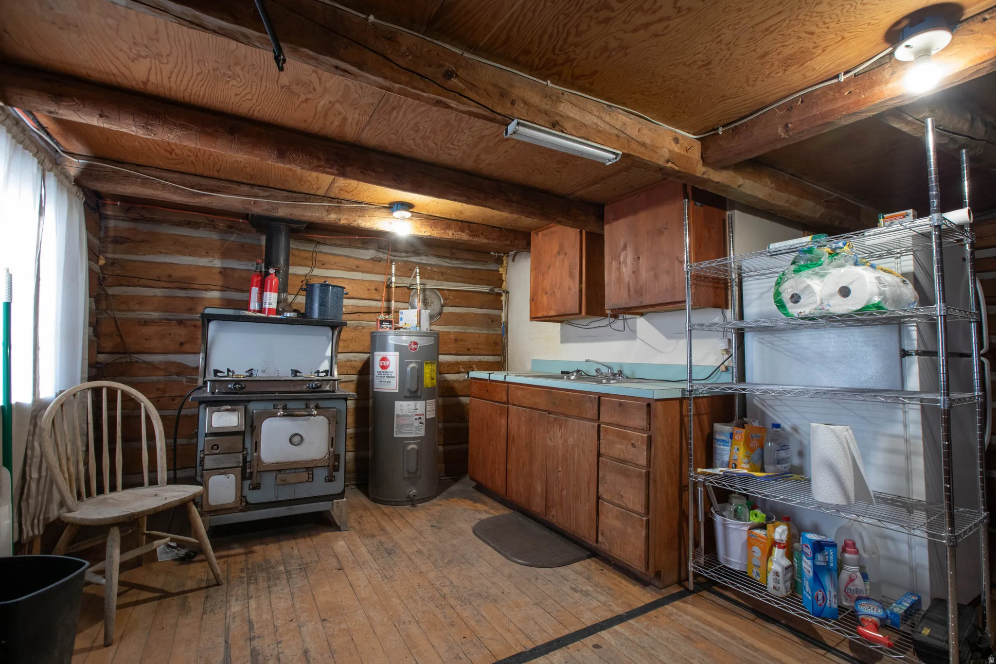Kitchen featuring light wood-style floors, light countertops, wood finish cabinets, and electric water heater