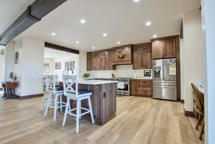 Kitchen with stainless steel appliances, a kitchen breakfast bar, light wood finished floors, a kitchen island with sink, and recessed lighting