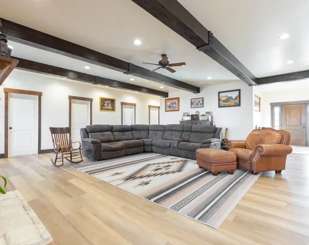 Living area featuring a ceiling fan, wood finished floors, recessed lighting, and beamed ceiling