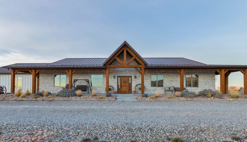View of front of property featuring a porch, stone siding, and a metal roof