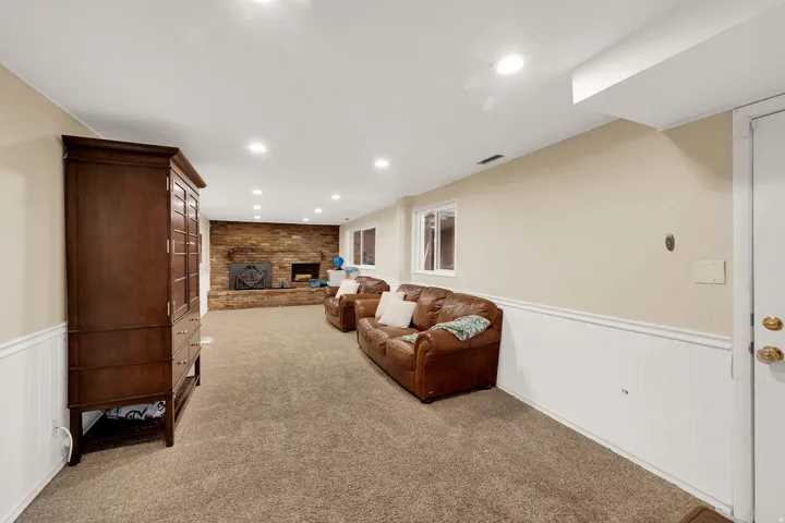 Living area featuring a wainscoted wall, recessed lighting, light carpet, and a fireplace