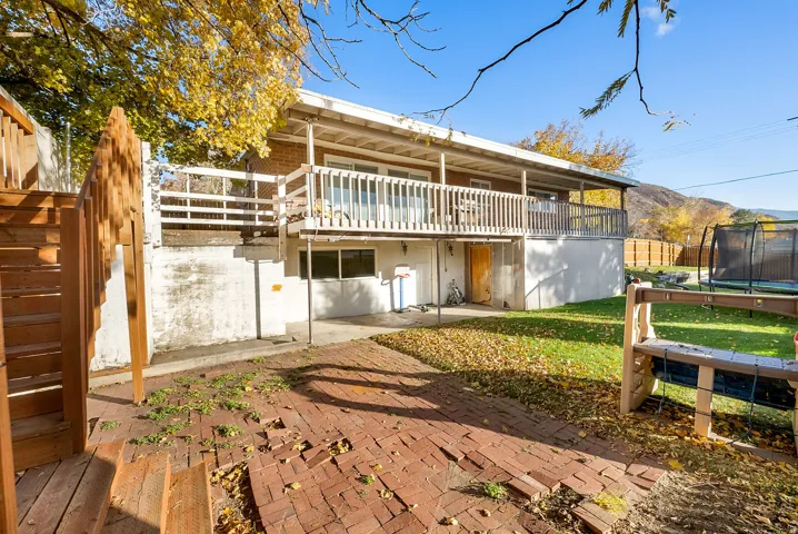 Rear view of house featuring a patio, a trampoline, and a mountain view