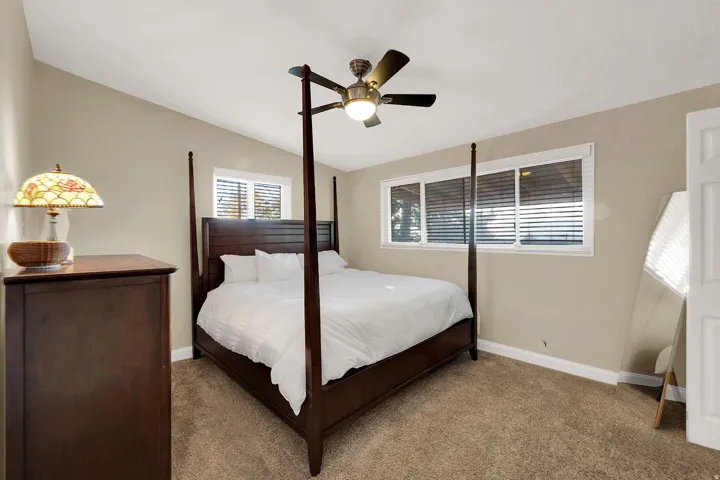 Carpeted bedroom featuring ceiling fan and lofted ceiling
