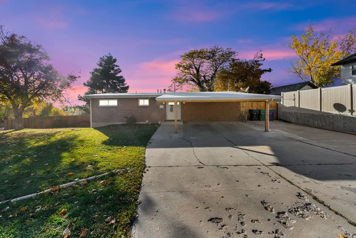 View of front of home with brick siding, driveway, and a carport