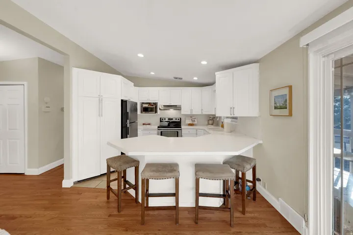 Kitchen featuring a peninsula, light countertops, stainless steel appliances, light wood-style floors, and white cabinets