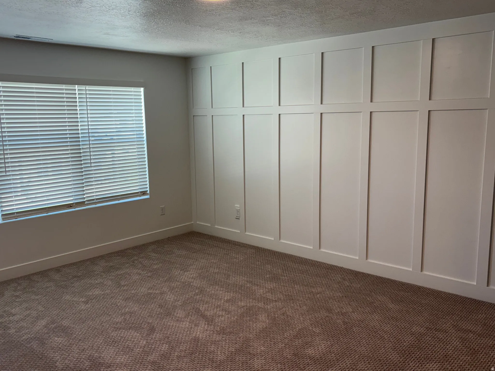 Spare room featuring dark carpet and a textured ceiling