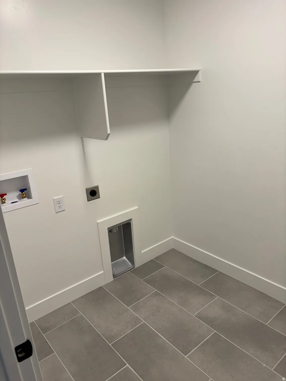 Laundry area with dark tile patterned floors, washer hookup, and hookup for an electric dryer