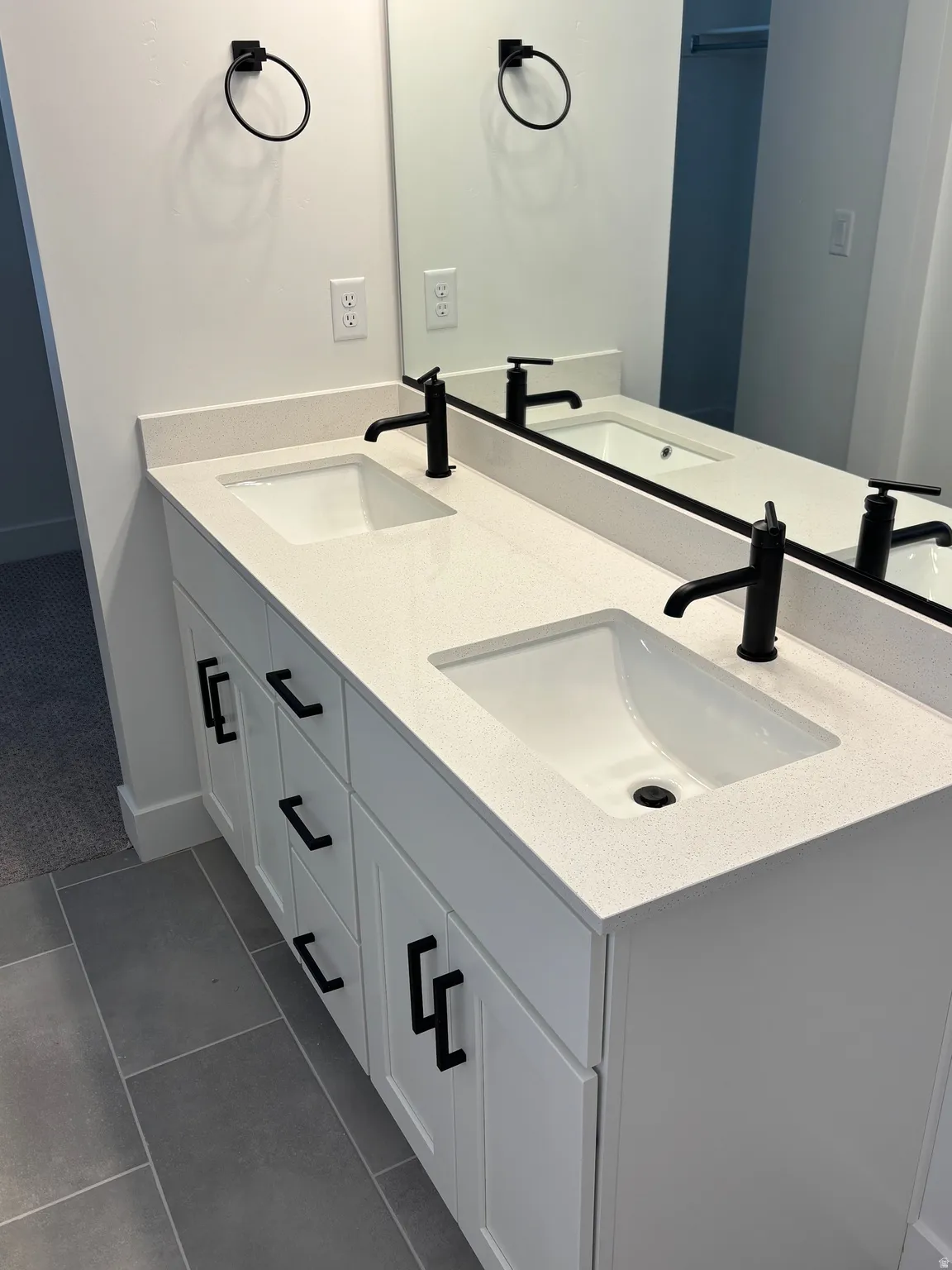 Bathroom with double vanity and dark tile patterned floors