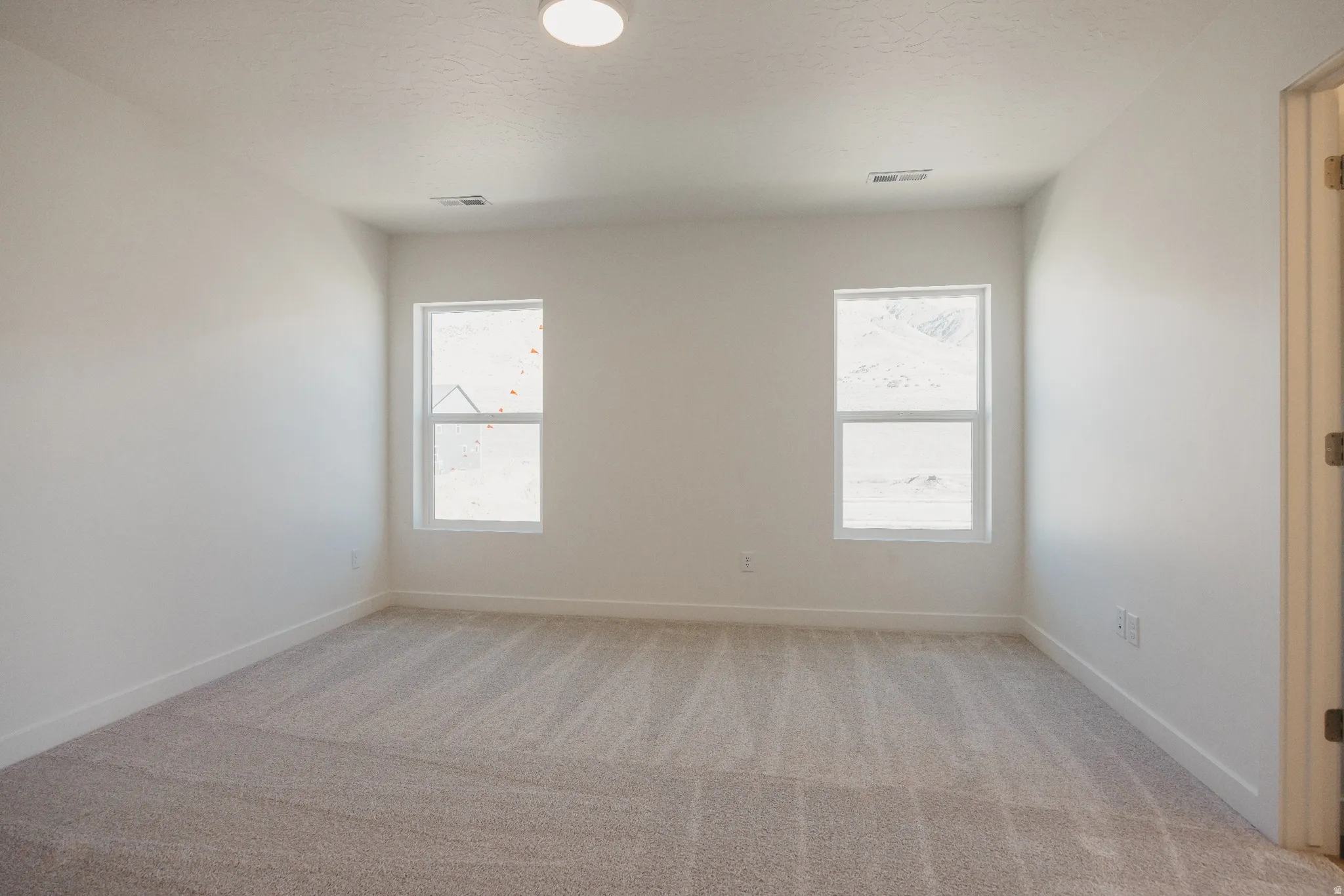 Empty room featuring light colored carpet and baseboards