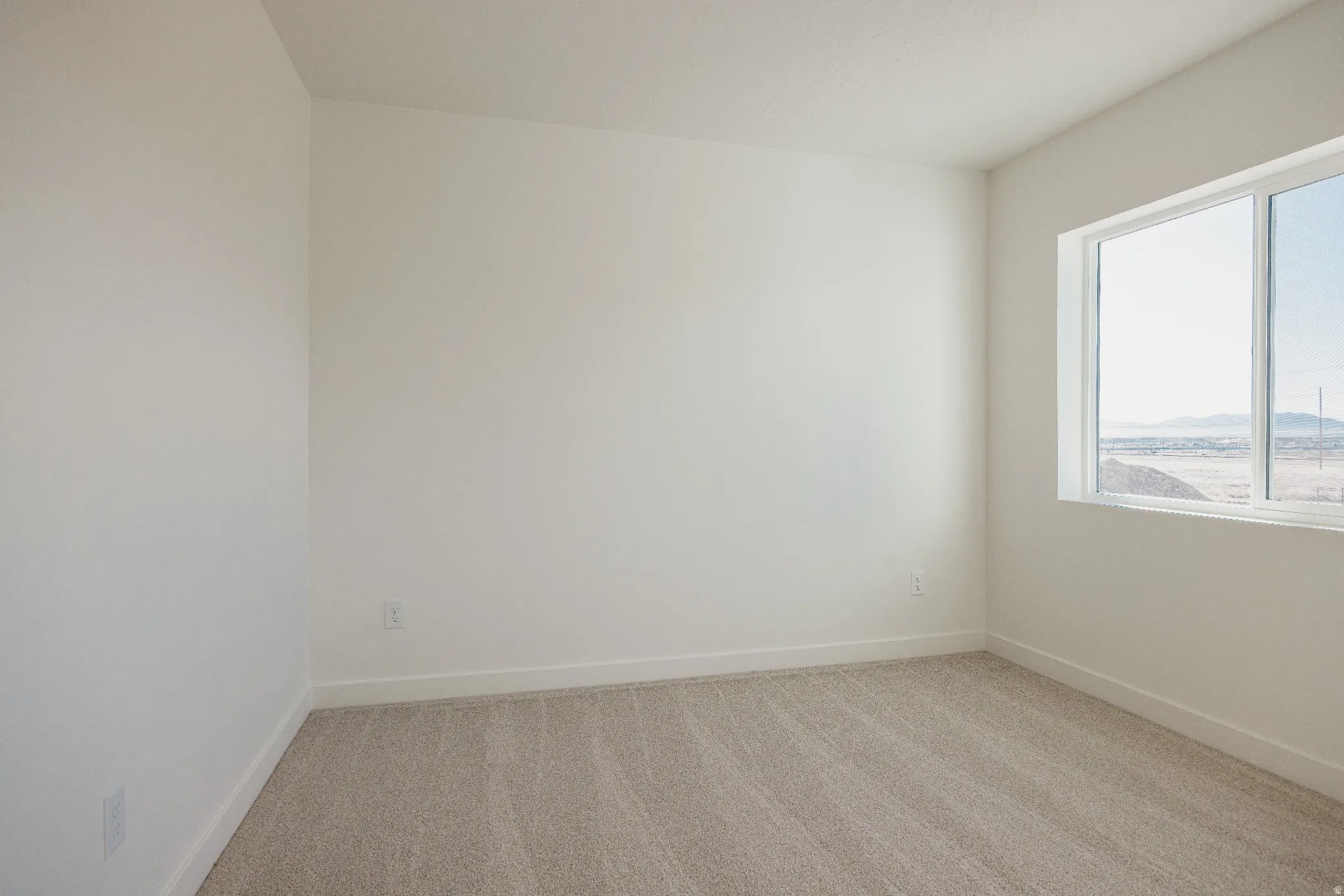 Empty room with light carpet and baseboards