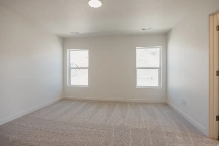 Empty room featuring light colored carpet and baseboards
