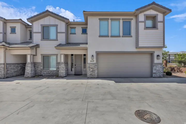 View of front facade with stone siding, driveway, an attached garage, board and batten siding, and stucco siding