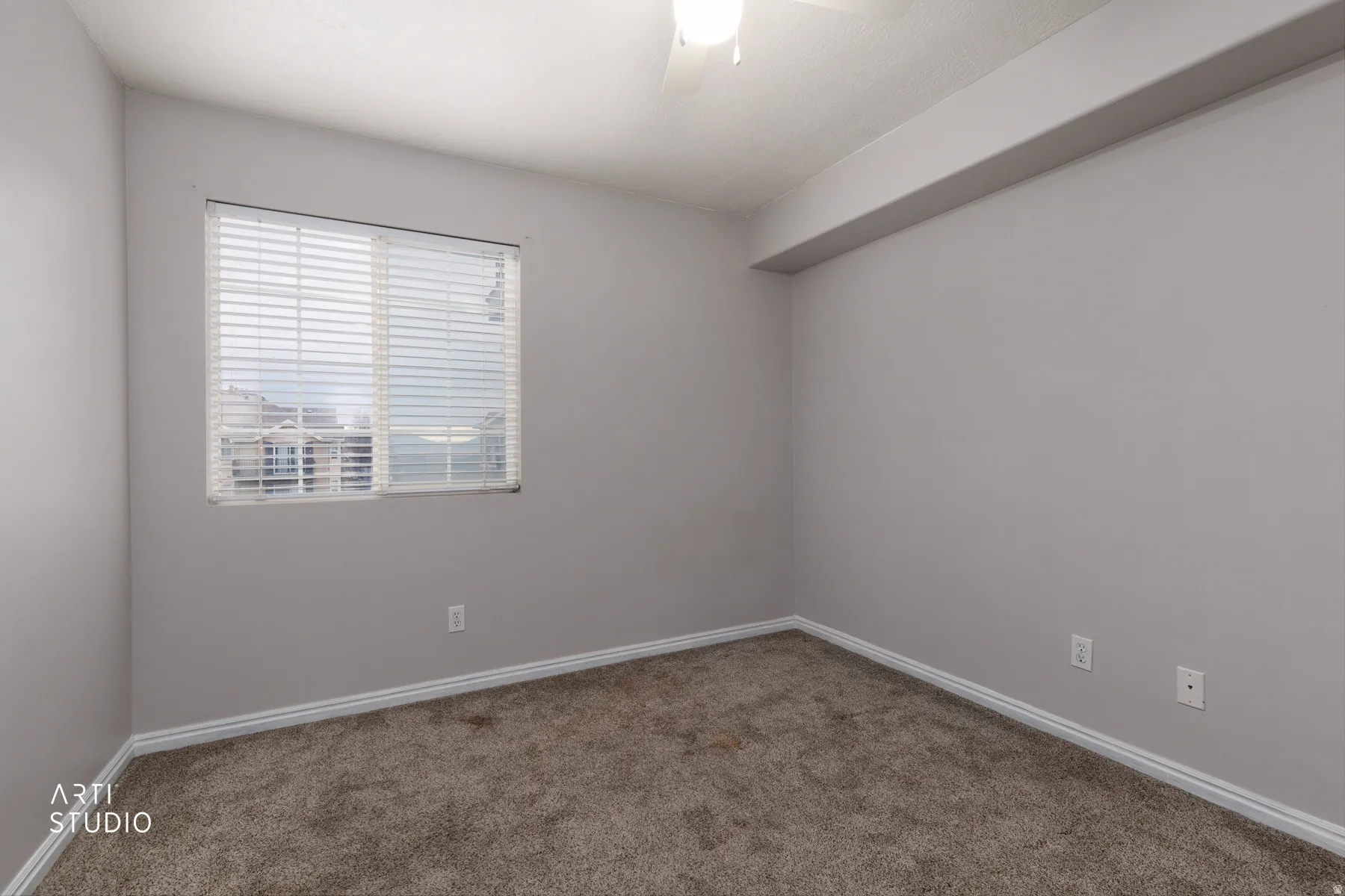 Carpeted spare room with ceiling fan and baseboards