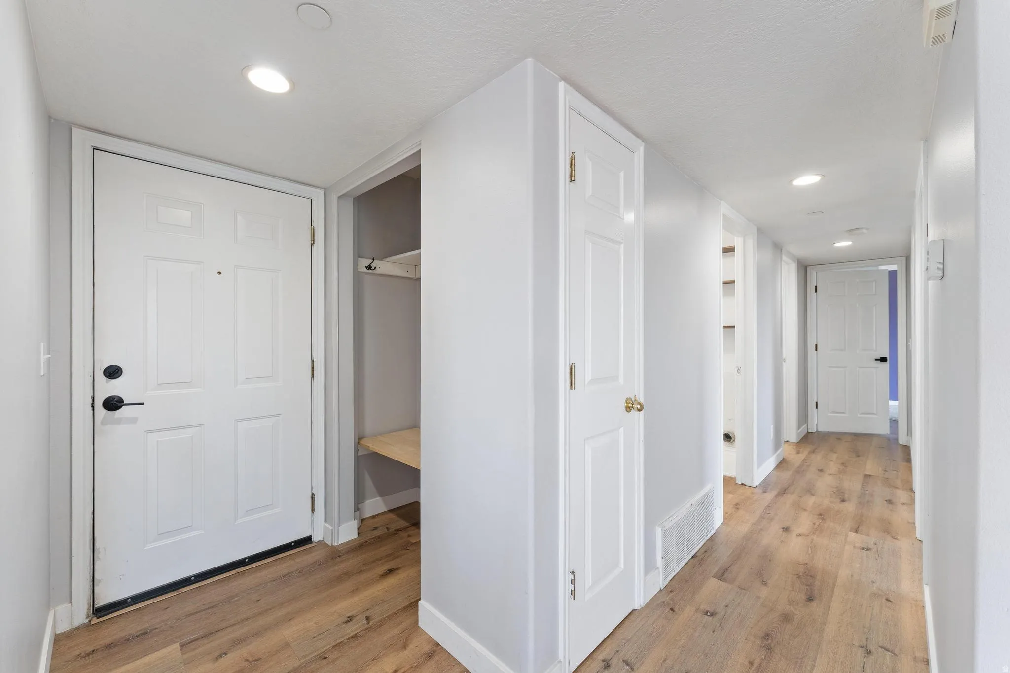 Hallway with light wood-style floors and recessed lighting