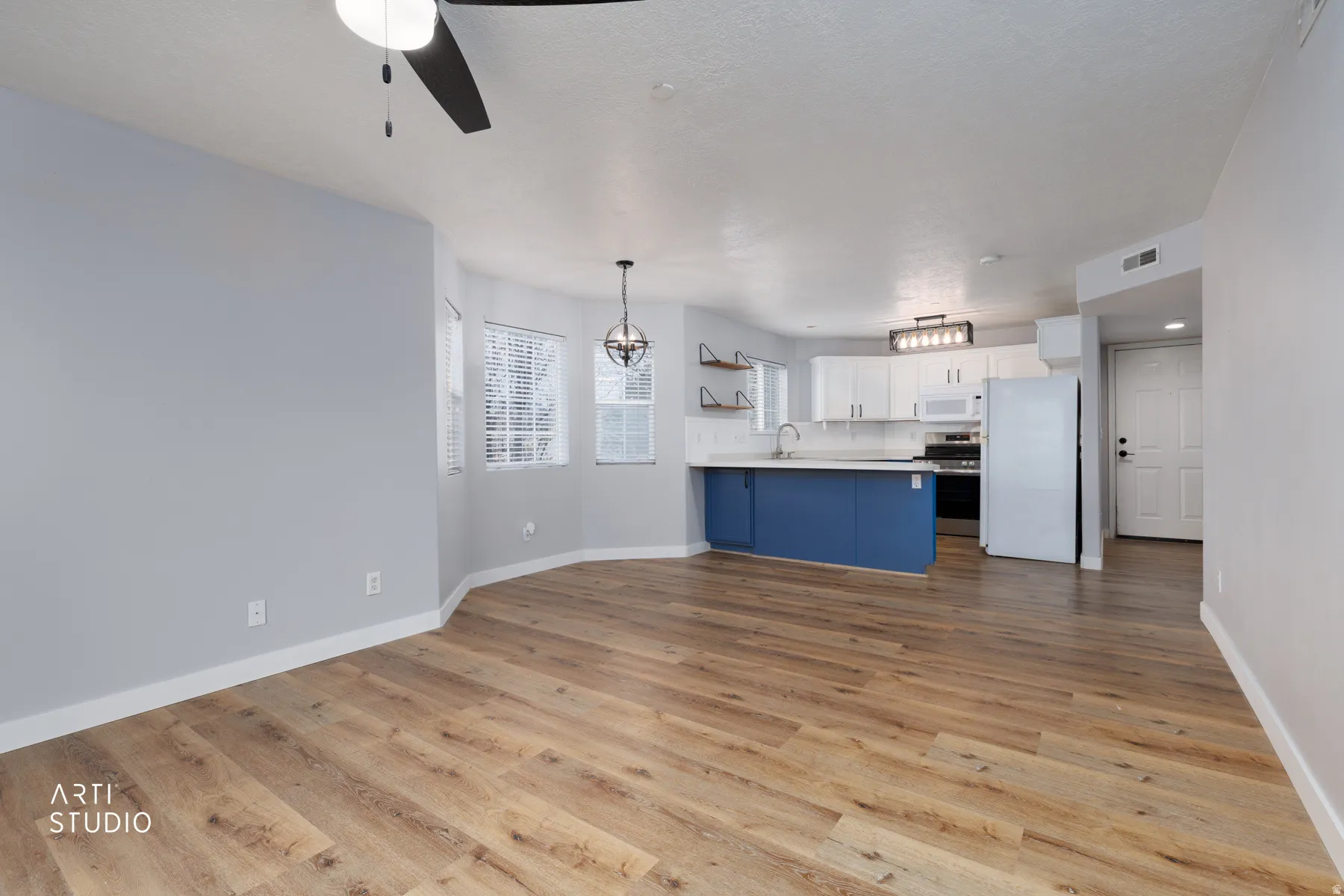 Kitchen with open floor plan, white appliances, blue cabinetry, light countertops, and ceiling fan