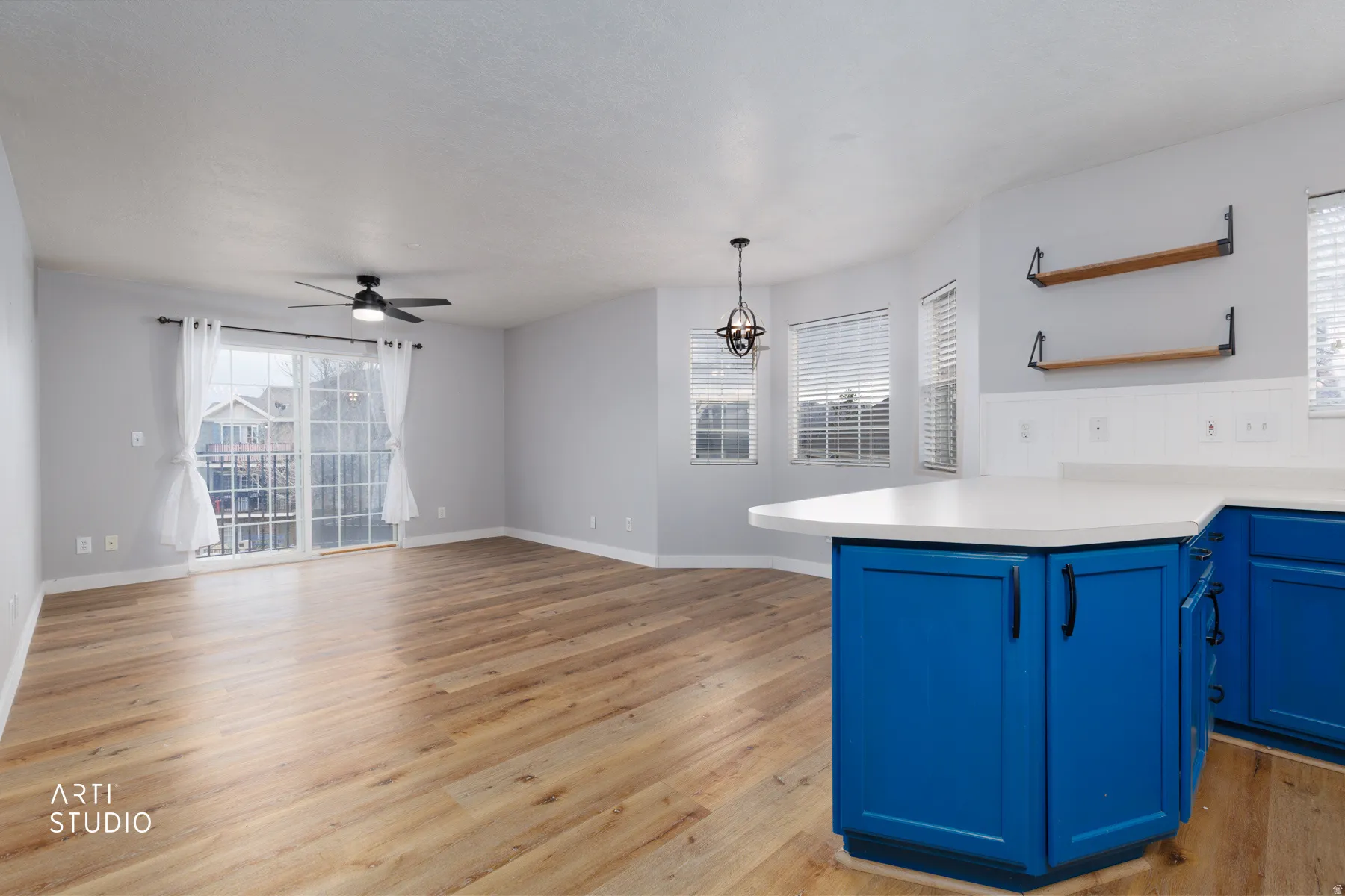 Kitchen with a peninsula, light countertops, a ceiling fan, light wood-style floors, and open shelves