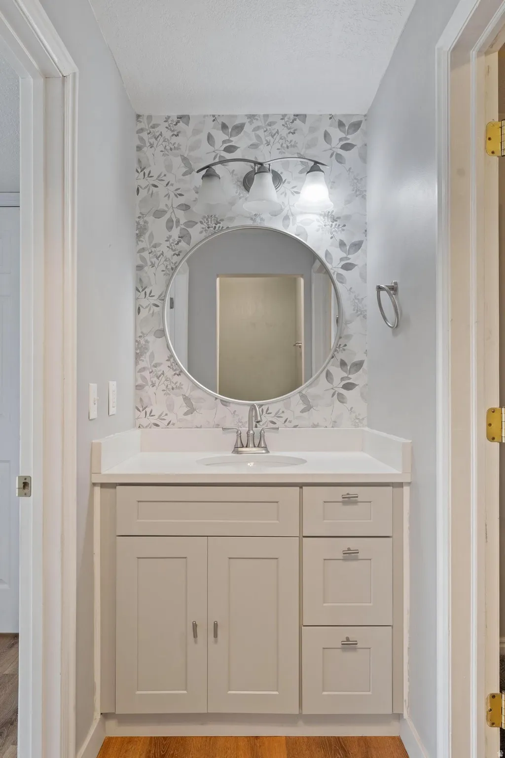 Bathroom with vanity, light wood-style floors, and a textured ceiling