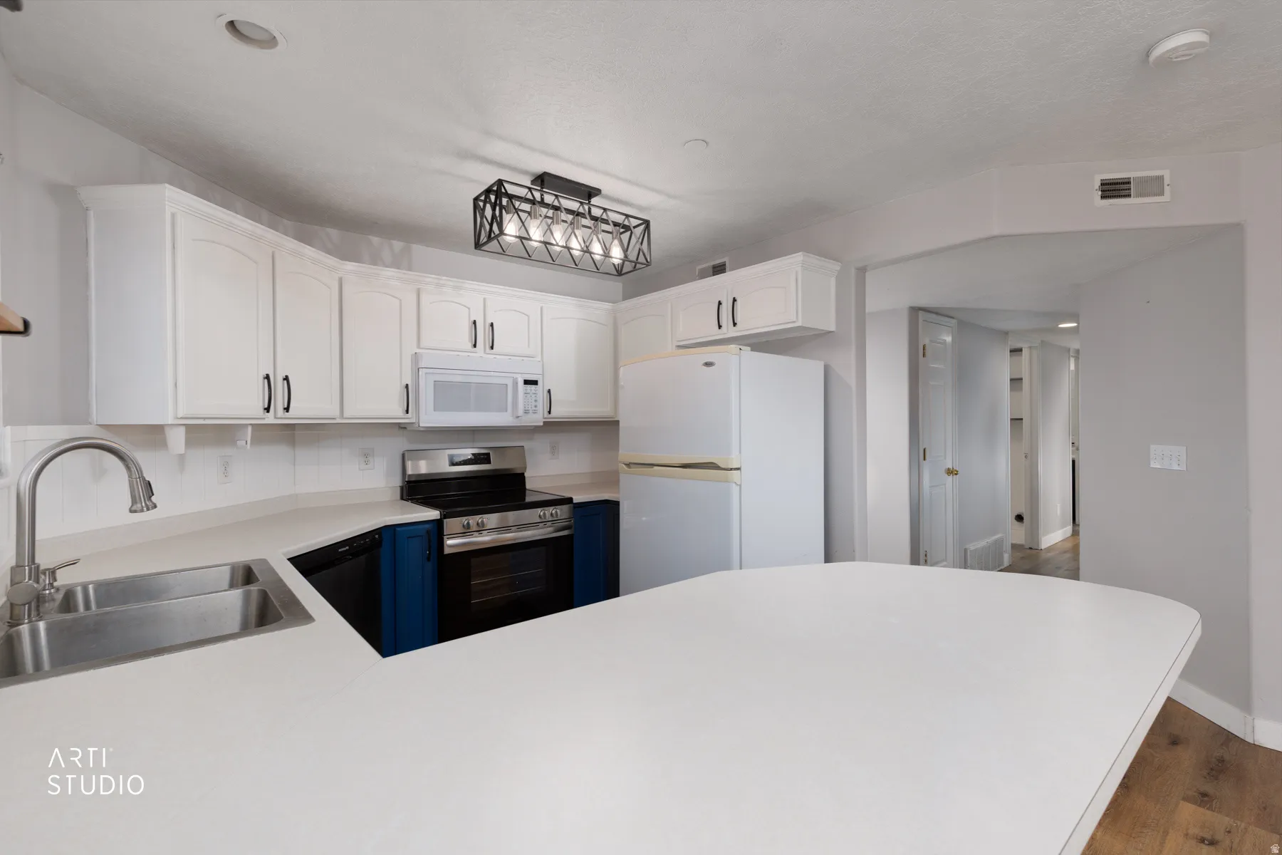Kitchen featuring light countertops, white appliances, dark wood-type flooring, a peninsula, and two tone color scheme