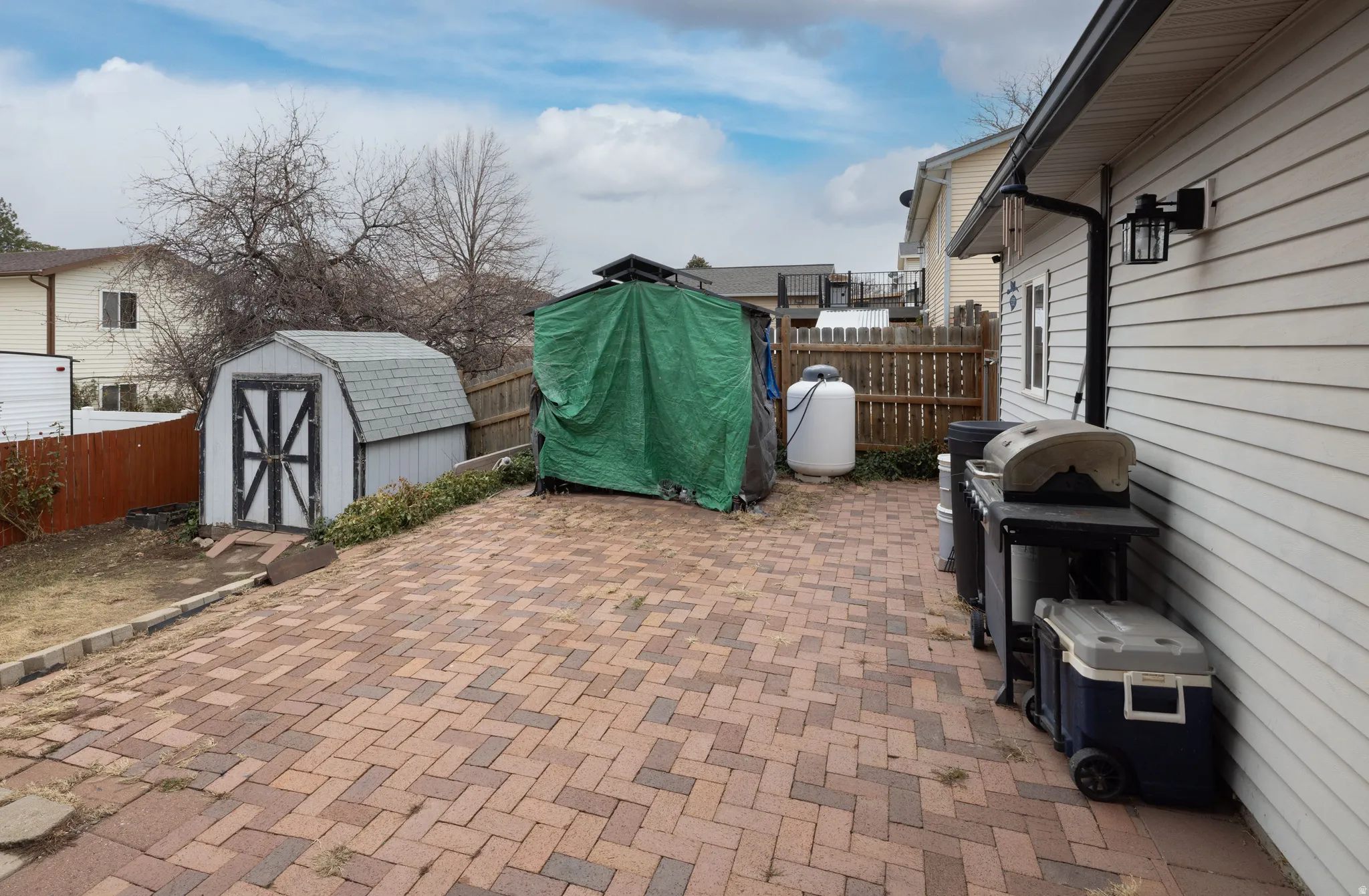 Fenced backyard featuring grilling area and a shed