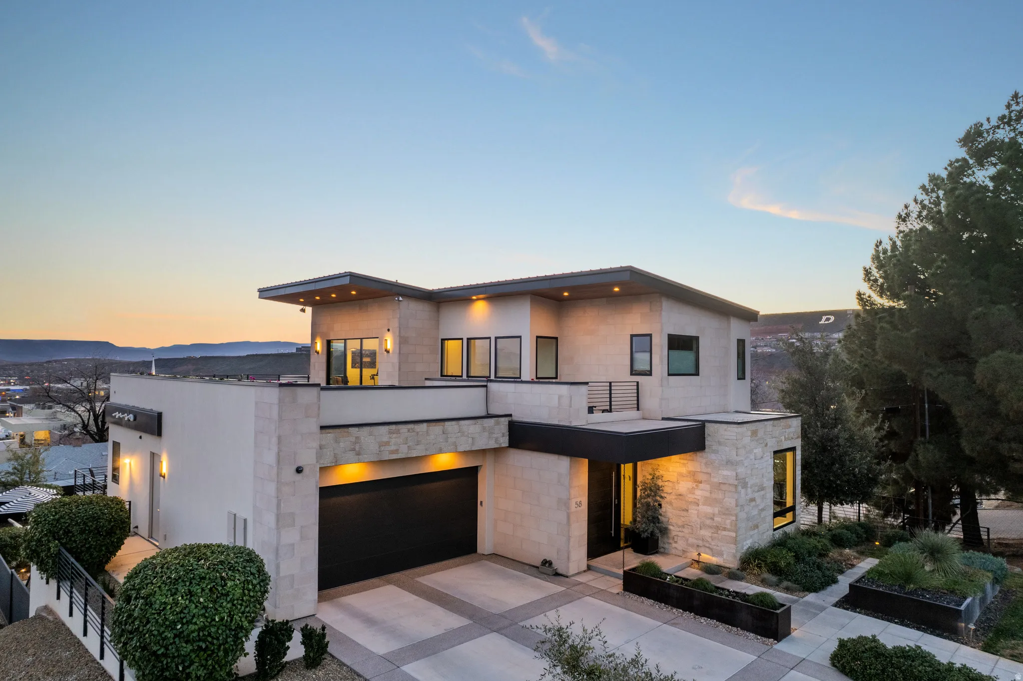 Contemporary house featuring a garage, concrete driveway, concrete block siding, and a balcony