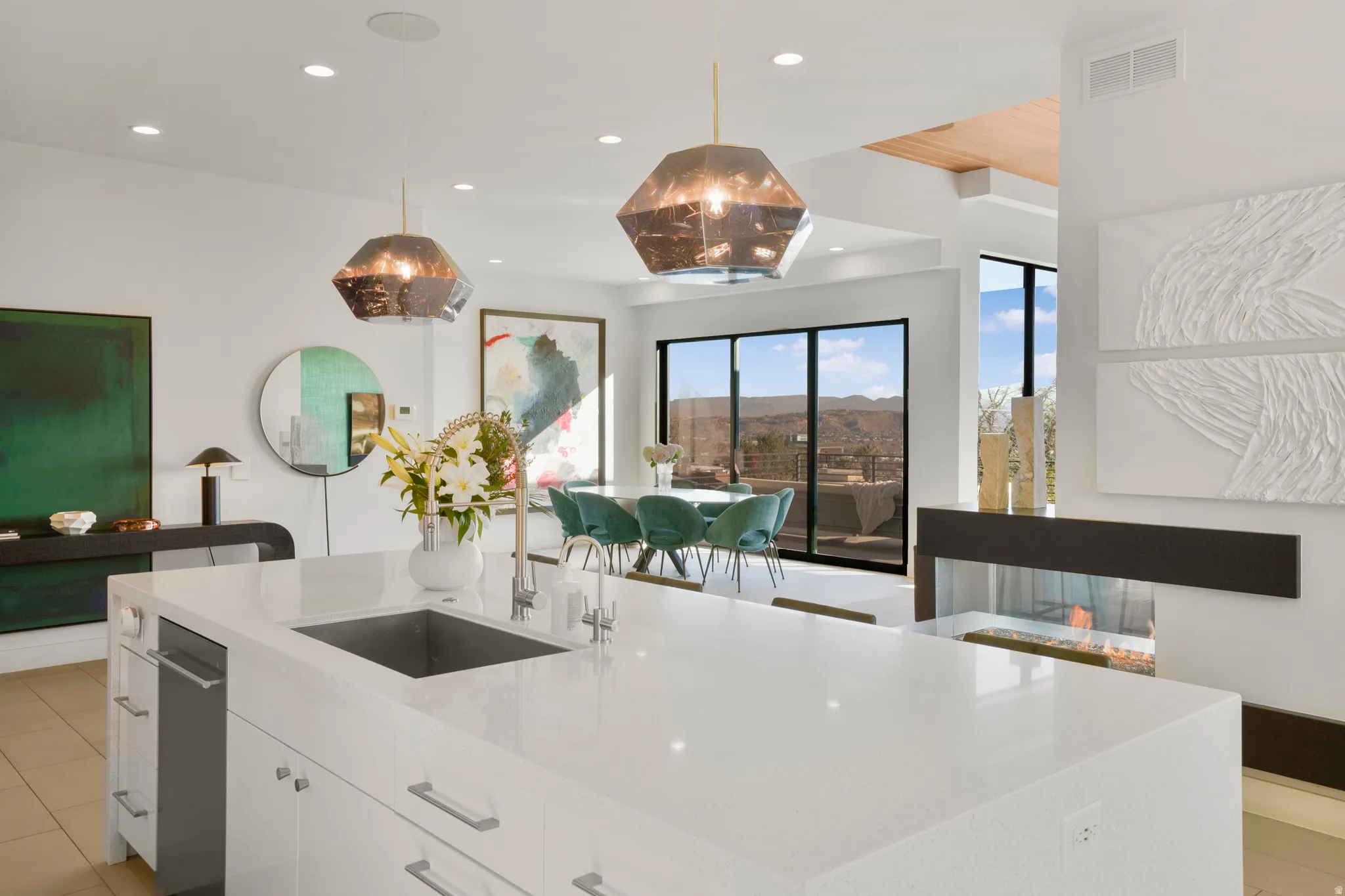 Kitchen with white cabinets, light stone countertops, and hanging light fixtures