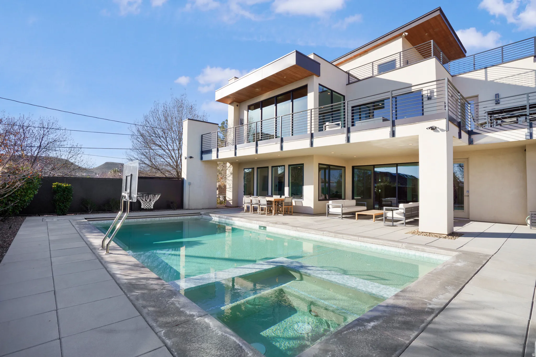 Back of property with a pool with connected hot tub, stucco siding, an outdoor living space, and a patio